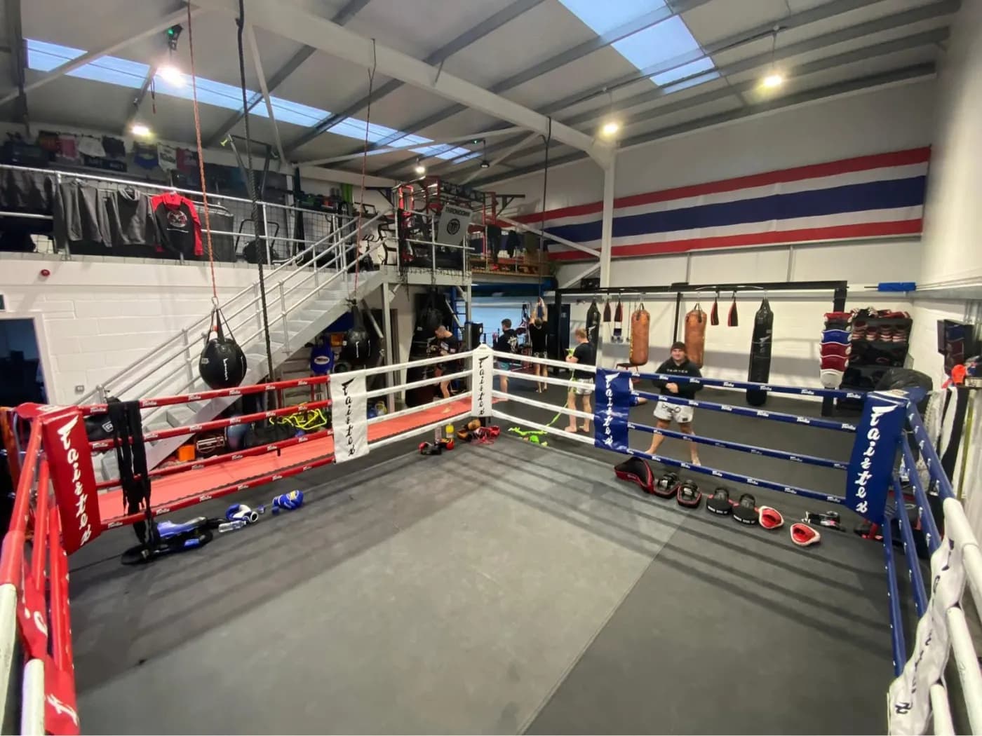 Two Fairtex rings on the main matted training floor under the Thai flag